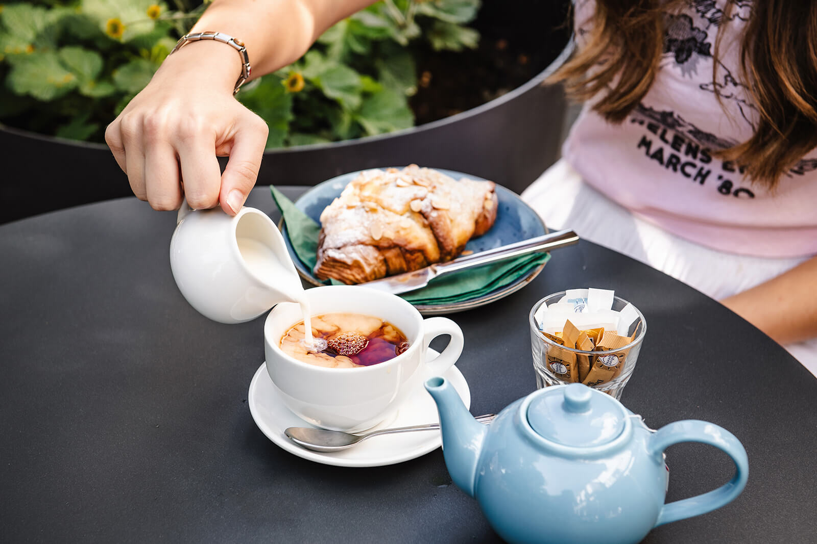 Almond croissant on a plate, teapot and tea poured into a teacup at the Phil cafe in the Pantiles
